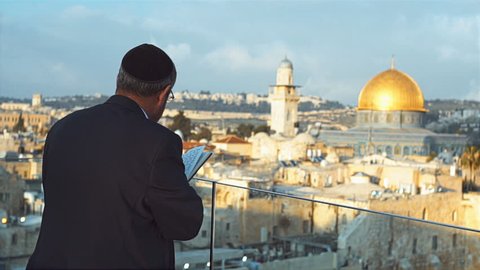 Jewish man praying in front of the Western Wall 
with background of dome of rock