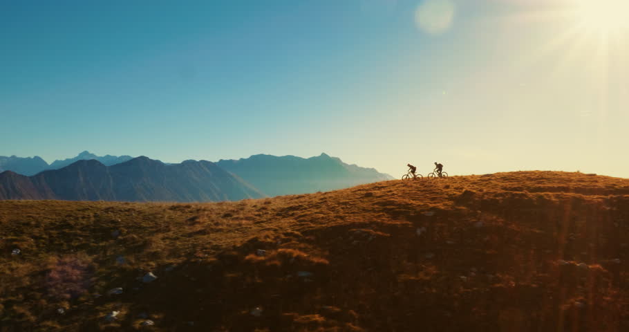 Aerial tracking of mountain bikers on cross-country cycling in amazing sunlight. | Shutterstock HD Video #1010578181