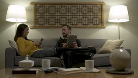 Couple lounging on sofa at home using mobile phone and doing crossword puzzle. - Powered by Shutterstock - Get 15% off with code: PIKWIZARD15