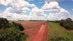 Fast drone aerial follow a convoy of tractors and farming equipment traveling down a small dirt road between fields on a sunny day in the rural countryside - Powered by Shutterstock - Get 15% off with code: PIKWIZARD15