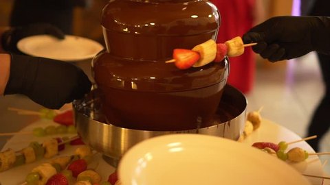 Party and celebration. People dipped strawberries in chocolate fountain. Celebration.