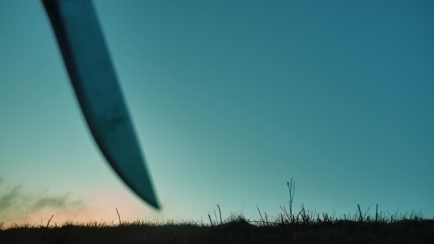 silhouette of a man in a hood with a knife. Shadow blur of horror man in jacket with hood facing side body and show the knife in his hand. A dangerous thug with a knife killer bandit lifestyle