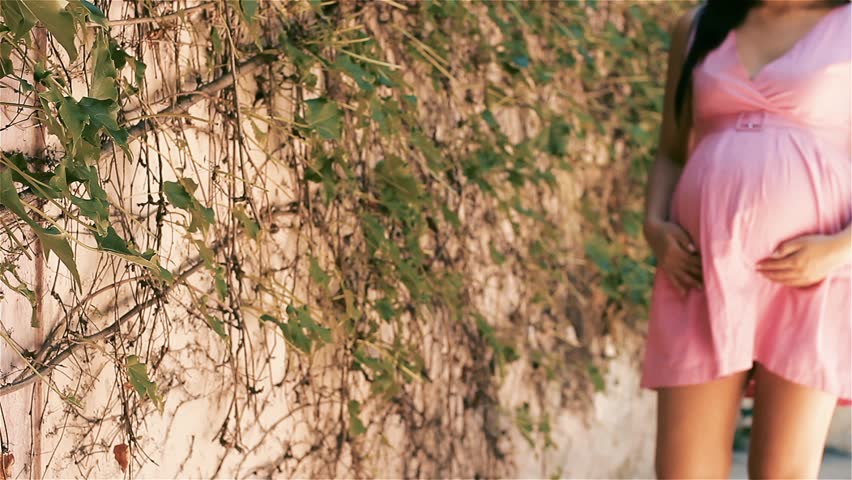Pregnant Woman Walking Along Ivy Covered Wall, Summer Maternity Scene