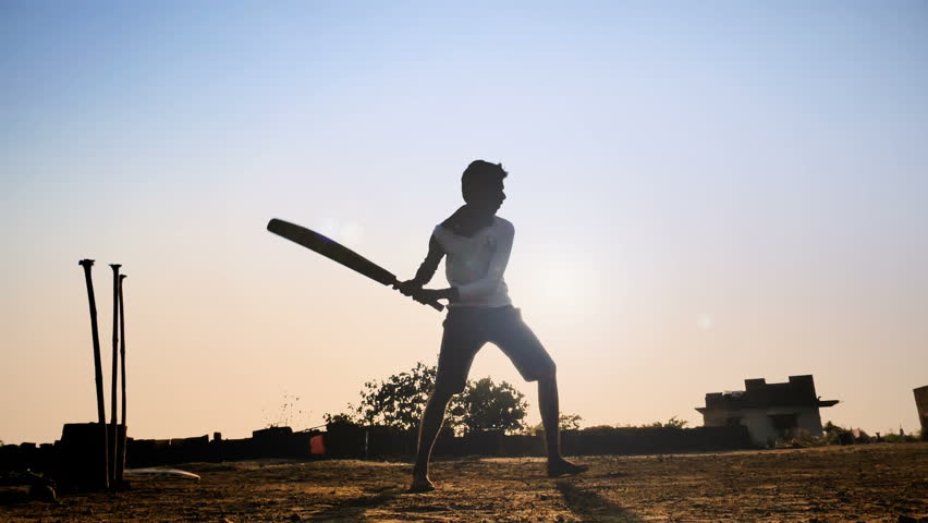 slow motion shot of young village teenager playing bare feet in a open field hits the cricket ball and runs. a silhouette shot of young man playing cricket in a summer vacation Royalty-Free Stock Footage #1010584862