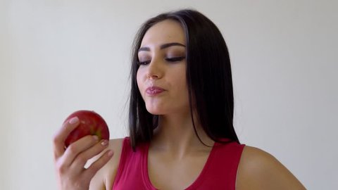 beautiful brunette girl eats Red Apple on a white