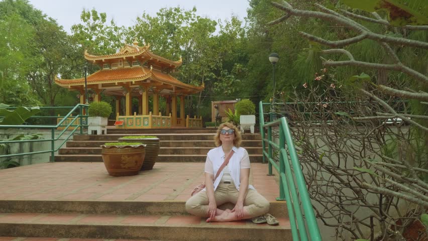 White woman prays at altar of Buddhist temple in Thailand