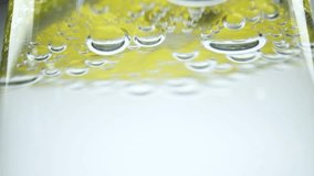 Macro slow motion video of air bubbles in soda water with lemon. White background. 4K