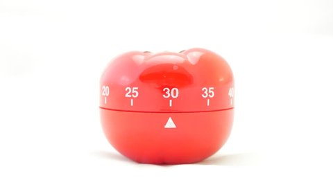 Time lapse footage of a tomato shaped kitchen timer on a 30 minute countdown , isolated on a white background.