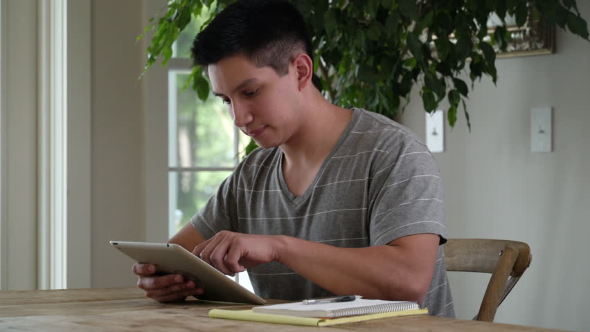 Young man at table using digital tablet.