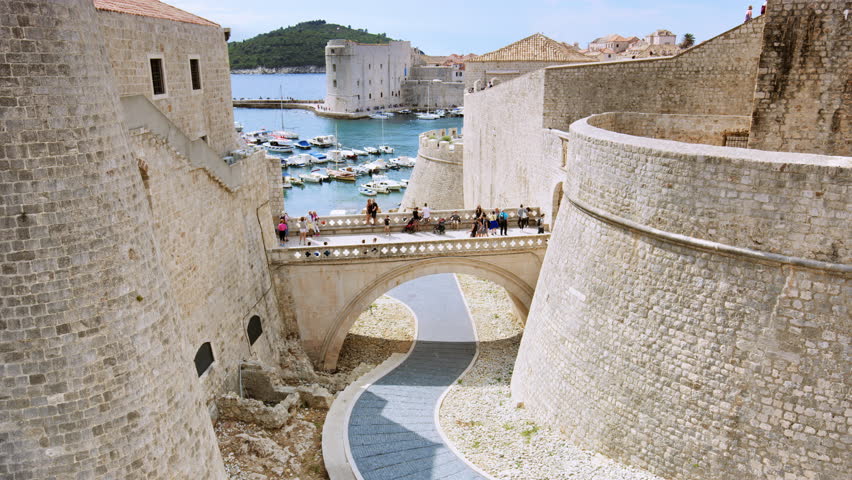 The sun is shinning on Dubrovnik’s inner gate bridge connecting Fort Revelin to Ploce Gate, with the Old Harbour and the Adriatic Sea in the background/Dubrovnik, Croatia. Shot with RED Weapon Helium.