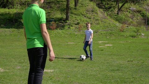 Three brothers play football in summer park
