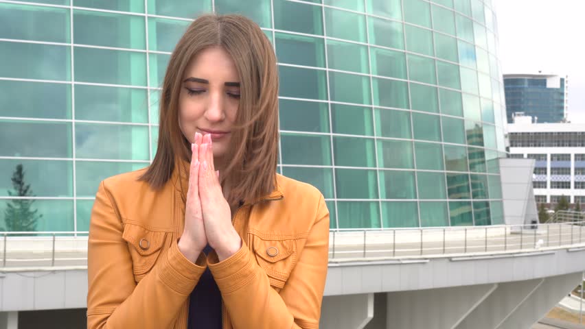 Portrait of real people, very beautiful girl praying at camera outdoor in the city. 4k