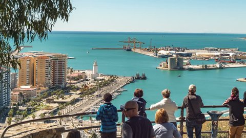 Malaga, Spain. Circa April 2018. Timelapse of tourists taking pictures in the viewpoint. The port , lighthouse and marina in the background.