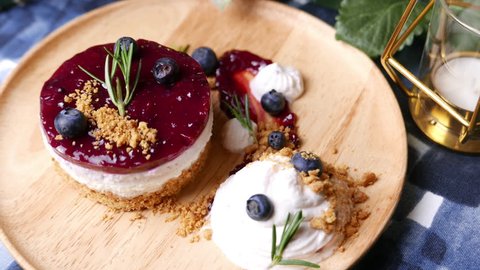 Delicious homemade cheesecake with berry sauce set on wooden plate.