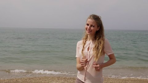 blonde woman dances and laughs at the beach