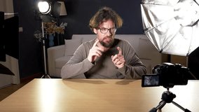 Man starting presentation of his channel of blogger in front of camera surrounded by lights