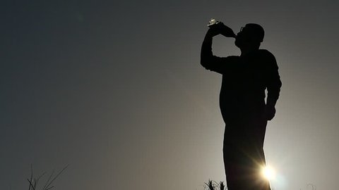Thirst - man drinking from bottle silhouette slow motion