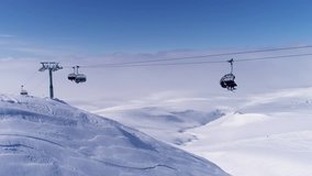Aerial view. Ski resort. Skiers and snowboarders climb the ski lift up the hill with snow-covered mountains Carpathians. Overhead cable car traffic on snow-covered mountain. ski lift wit the mountain 