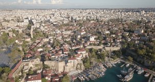 High altitude aerial drone video Kaleici old town reverse to reveal ships in waterfront harbor and Mediterranean Sea in Antalya, Turkey. 4k at 23.97fps
