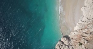 Forward aerial drone video top down bird's eye view along shoreline of Kaputas Beach and waves breaking on Turquoise Coast near Kas, Turkey. 4k at 23.97fps