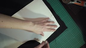 Manufacture of clothes at a garment factory. Chalked around the paper drawing. Tailor at work, drawing line on fabric with chalk. 4K video, circular motion camera.