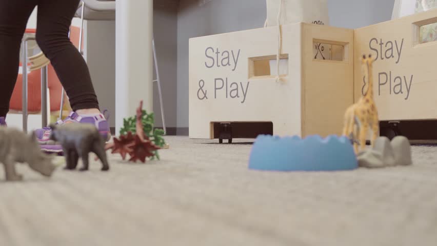 Little girl putting toys away into toy boxes at the local library.