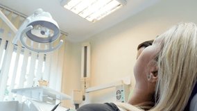 4k closeup video of dentist adjusting lamp and looking at patient sitting in chair