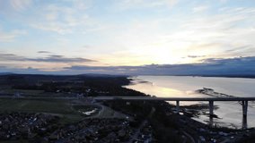 Aerial drone footage of Queensferry Crossing bridges over Firth of Forth bay and houses, Scotland, United Kingdom. 