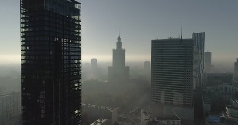 Drone footage in between office skyscrapers towards the Palace of Culture and Science. Shot is taken during a misty but sunny day in Polish capital city, Warsaw.

