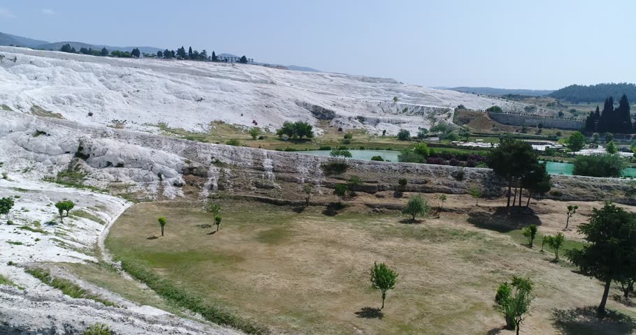 Aerial. Camera moves down . Pamukkale terraces or "cotton Castle". Brilliantly white calcium cliff. 4K.