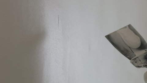 Slow motion handheld shot of worker applying putty on the wall