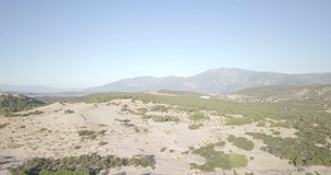 High elevation aerial drone video inland mountain landscape descend pedestal down to sand beach and dunes in Patara, Turkey. 4k at 23.97fps