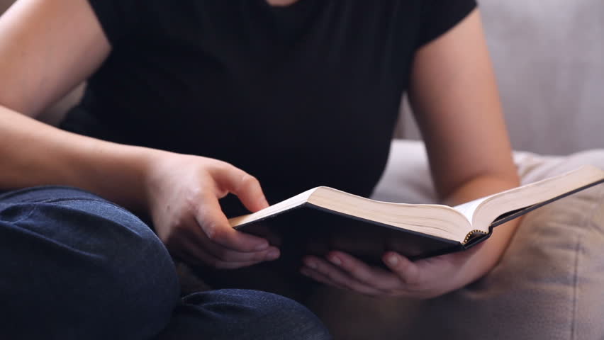 Young woman relaxing on the couch reading the Bible Royalty-Free Stock Footage #1010677805