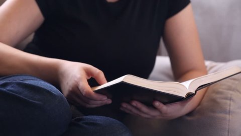Young woman relaxing on the couch reading the Bible