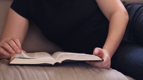 Young woman relaxing on the couch reading the Bible