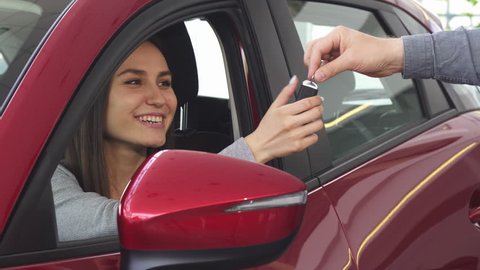 Young happy woman receiving car keys to her new automobile