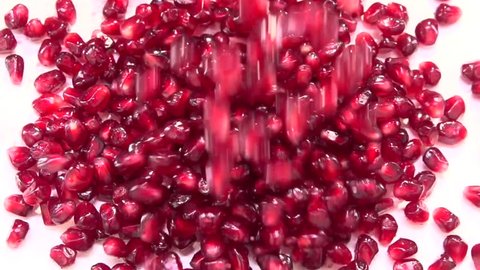 Garnet of grain. Pomegranate seeds falls and rolls on a white table.. Slow motion 240 fps. Slowmo. High speed camera shot. Full HD 1080p. 