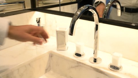 Man pouring water in elegant marble sink.