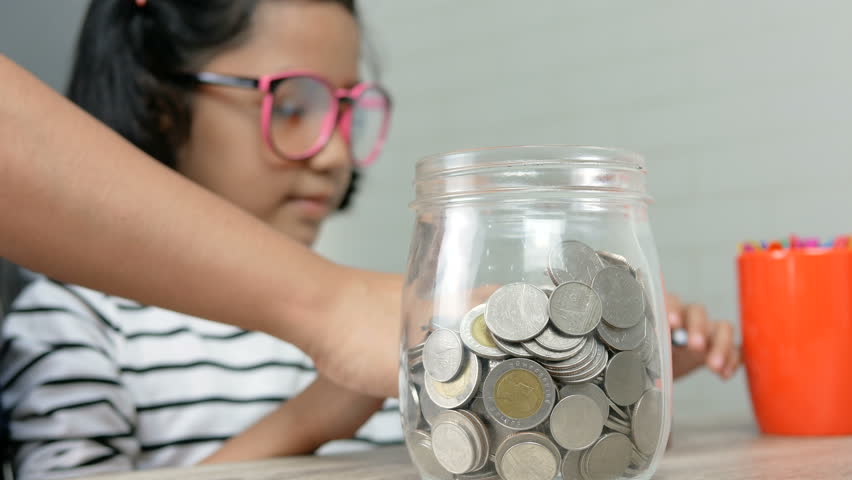 Asian little girl putting the coin in to a glass jar shallow depth of field select focus on jar
 | Shutterstock HD Video #1010696204