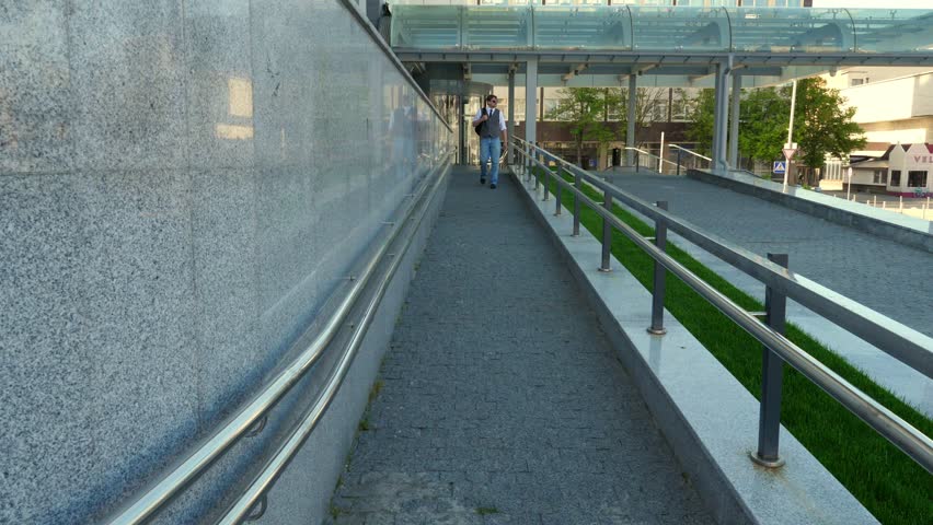A man with a backpack goes down the stairs. Young man. Tourist. Pensive. Corrects hair style