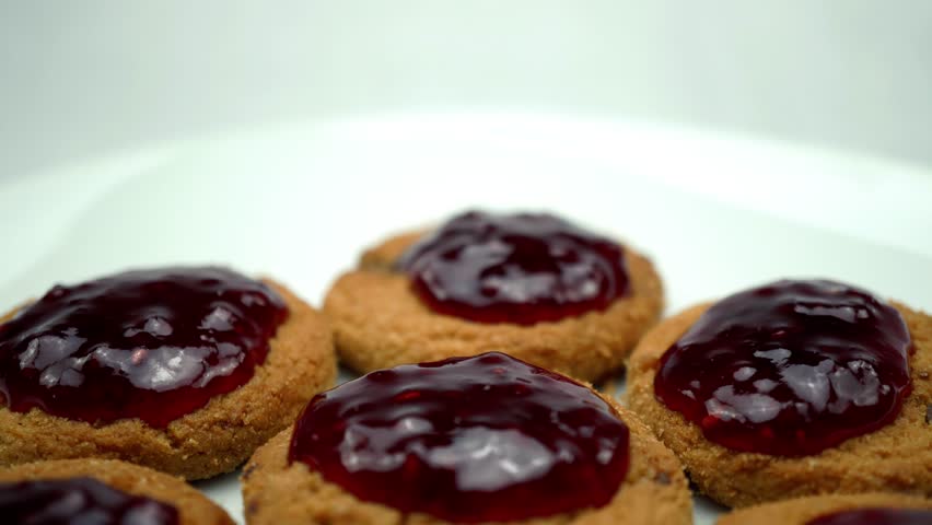 Raspberry jam on cookies. On a rotating white background. 4K 