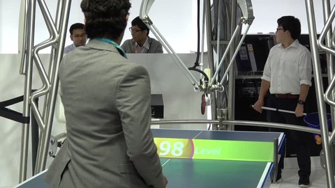 Hannover, Germany - April, 2018: Visitors playing ping-pong table tennis with robot Forpheus on Omron stand on Messe fair in Hannover, Germany