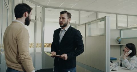 Two colleagues have a conversation in the office hall