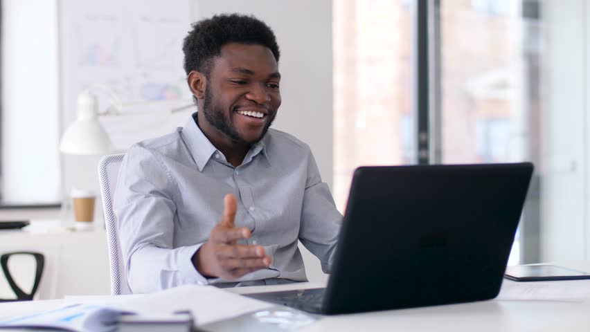 Business, technology and communication concept - happy smiling african american businessman having video chat on laptop computer at office | Shutterstock HD Video #1010703950