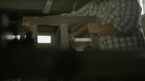 Slow motion shot of man sanding wood frame in workshop / Provo, Utah, United States