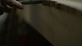 Slow motion tilt up to hands of man using chisel to detail edge of wood / Provo, Utah, United States