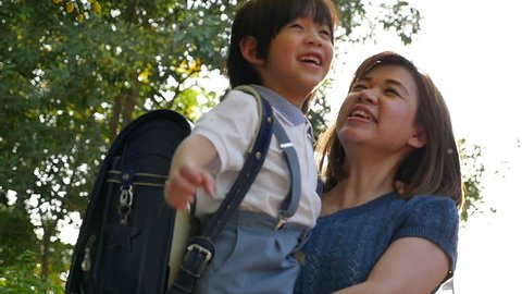 Asian mother holding her son while walking in the park , back to school concept slow motion – Stockvideo