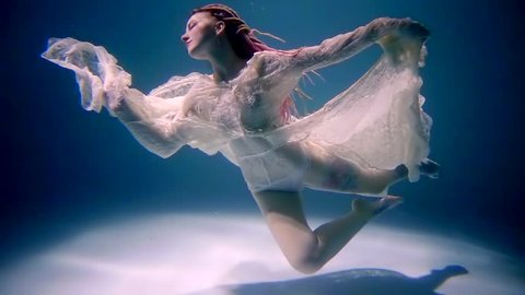 Stunning young model is floating in pose underwater.
