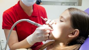Closeup 4k video of dentist using dental drill while treating teenager's teeth