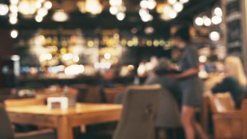 Blurred of interior of large beautiful restaurant with bright lighting. Waitress comes to table and gives visitors a menu and goes for drinks. Defocused restaurant. Lifestyle Royalty-Free Stock Footage #1010750342